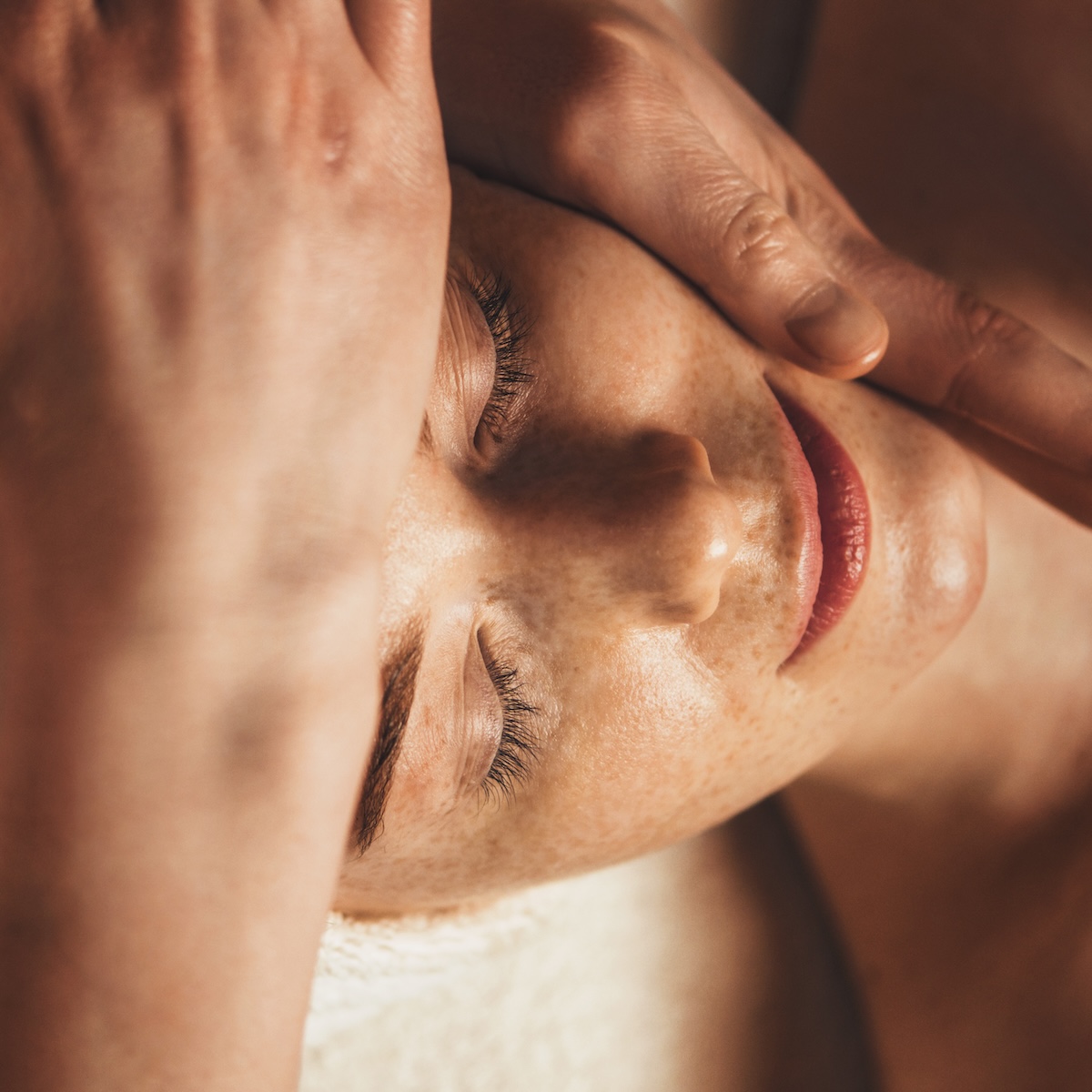 Beautiful freckled woman getting a face massage at beauty salon.
